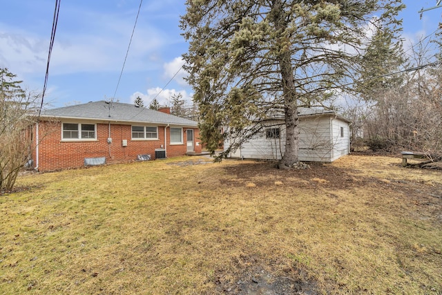 back of house with a chimney, brick siding, a yard, and central AC