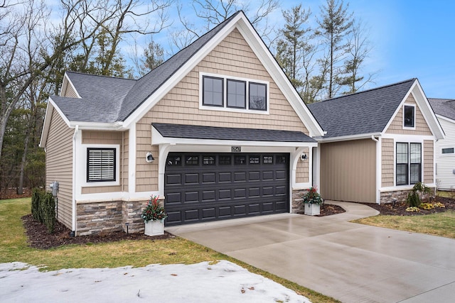 view of front of property with stone siding, roof with shingles, and concrete driveway