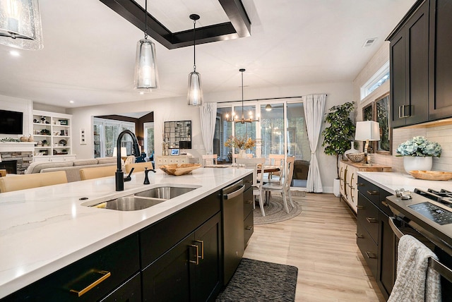 kitchen featuring decorative light fixtures, stainless steel appliances, backsplash, a sink, and a stone fireplace