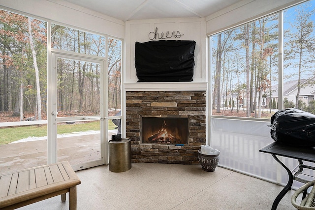 sunroom featuring a warm lit fireplace and plenty of natural light