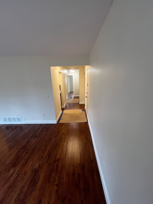 hall featuring visible vents, dark wood finished floors, and baseboards