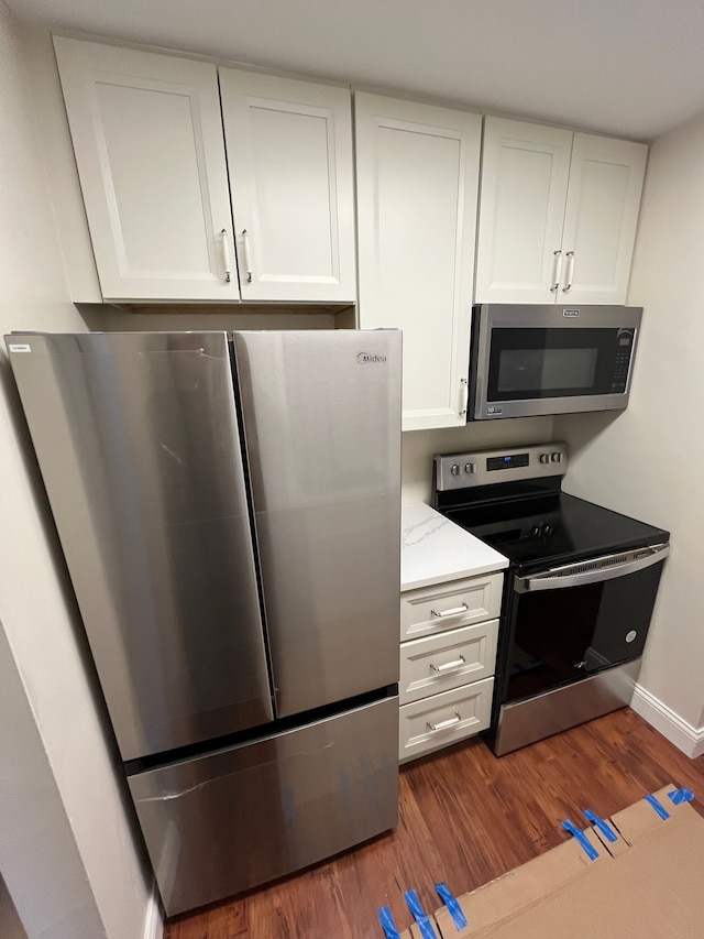 kitchen featuring appliances with stainless steel finishes, dark wood-style flooring, white cabinets, and light stone countertops