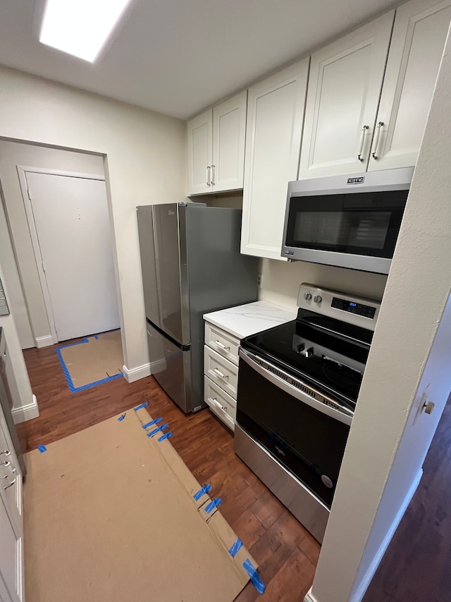 kitchen with baseboards, stainless steel appliances, wood finished floors, and white cabinets