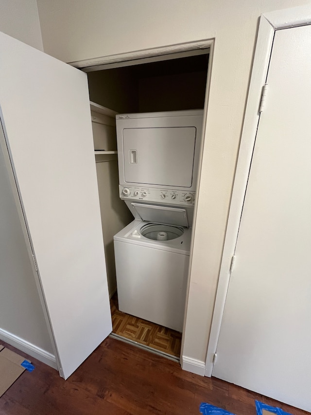 washroom featuring stacked washer and dryer, laundry area, and baseboards