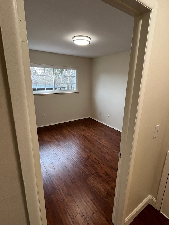 empty room featuring baseboards and dark wood-style flooring