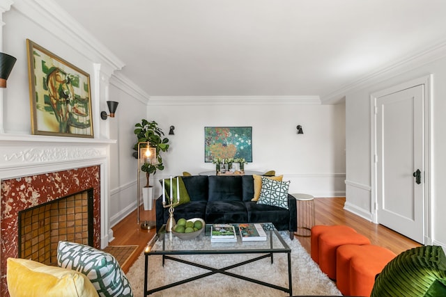 living area with ornamental molding, a tiled fireplace, wood finished floors, and baseboards