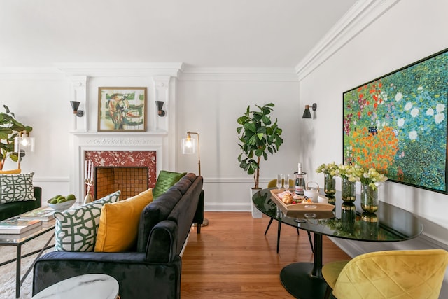 living room featuring baseboards, wood finished floors, crown molding, and a tile fireplace