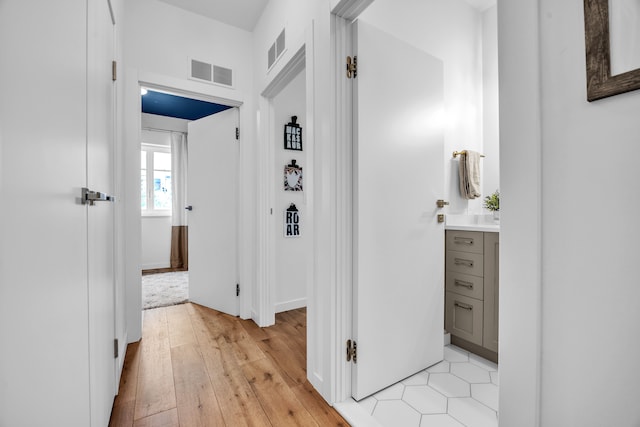 hall with light wood-style floors and visible vents