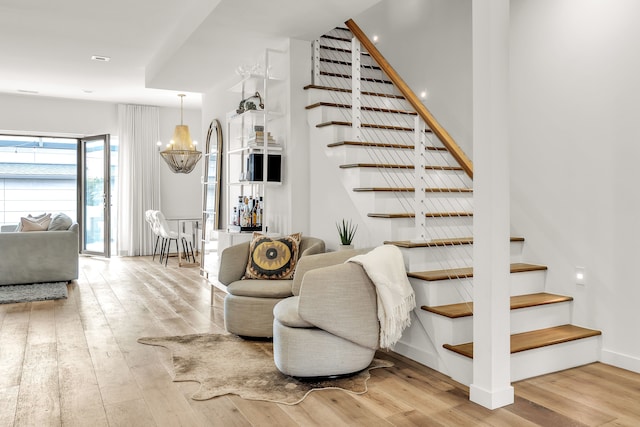 stairs with hardwood / wood-style flooring, baseboards, and a notable chandelier