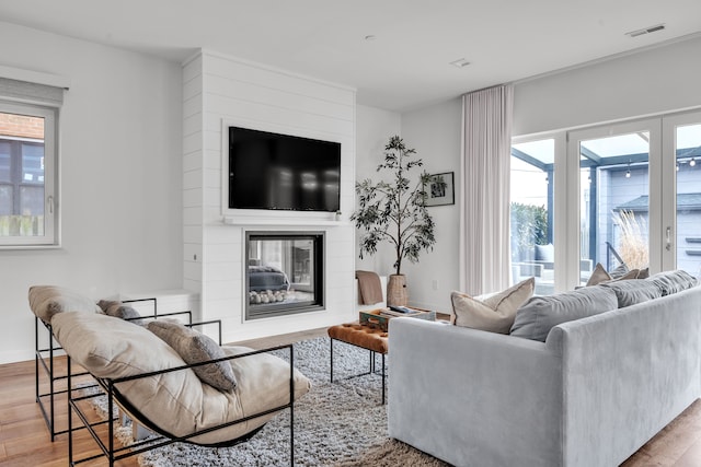 living area with a fireplace, wood finished floors, visible vents, and baseboards