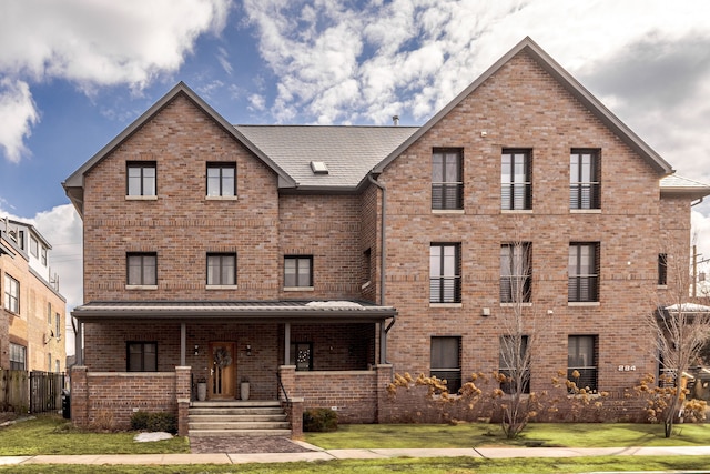 view of front of house featuring covered porch, brick siding, and a front lawn