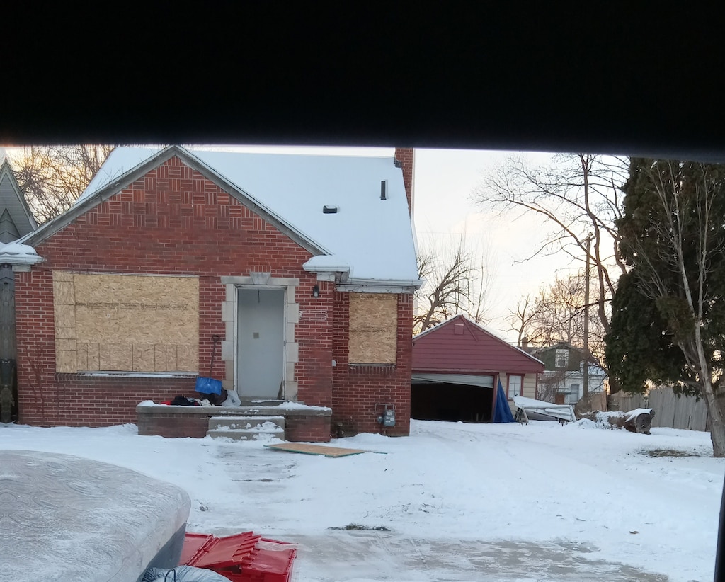 view of front of home with a garage, brick siding, and fence