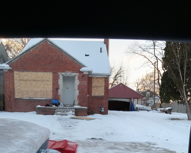 view of front of property featuring a detached garage, fence, and brick siding