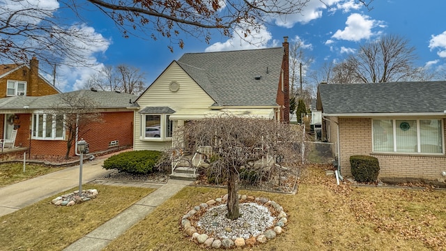 bungalow-style house with a shingled roof, a chimney, fence, and brick siding