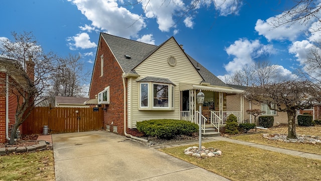 bungalow with a shingled roof, fence, and brick siding