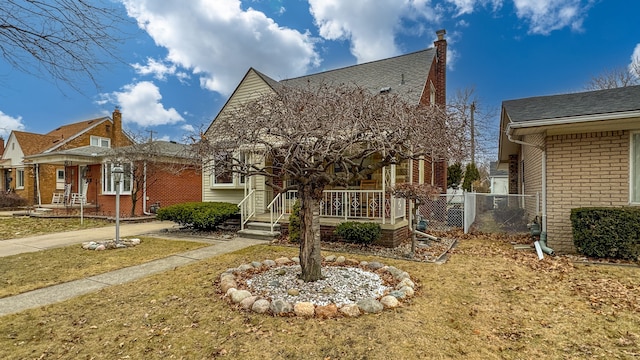 view of front of home with a chimney, roof with shingles, fence, a porch, and brick siding