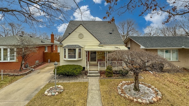 view of front of property featuring a shingled roof, a porch, and brick siding