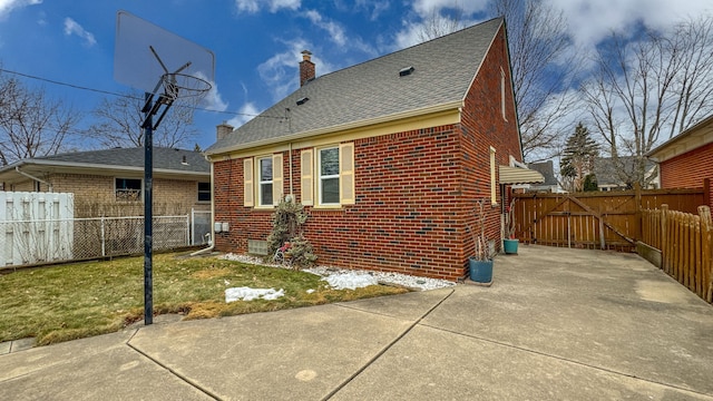 exterior space with a chimney, a gate, fence, and brick siding