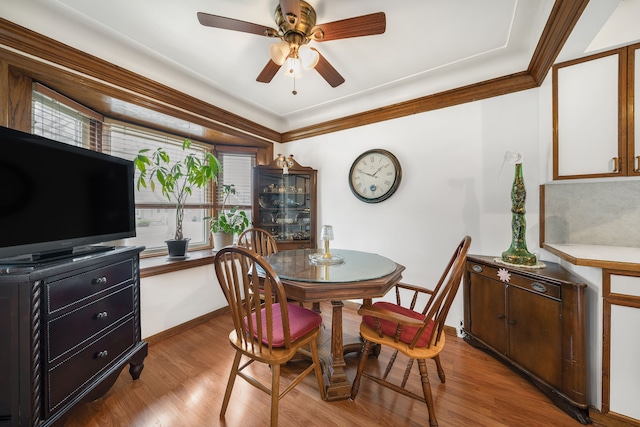 dining space featuring ornamental molding, a ceiling fan, baseboards, and wood finished floors