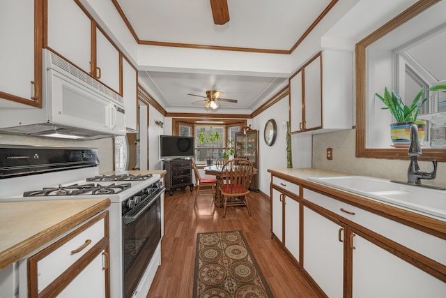 kitchen featuring white appliances, light countertops, crown molding, and a sink