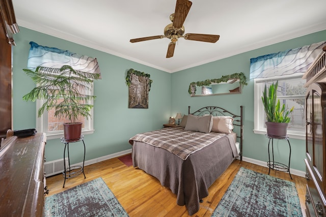 bedroom with a ceiling fan, visible vents, baseboards, and wood finished floors