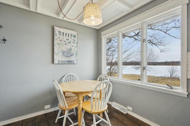 dining area with dark wood-type flooring, a water view, visible vents, and baseboards