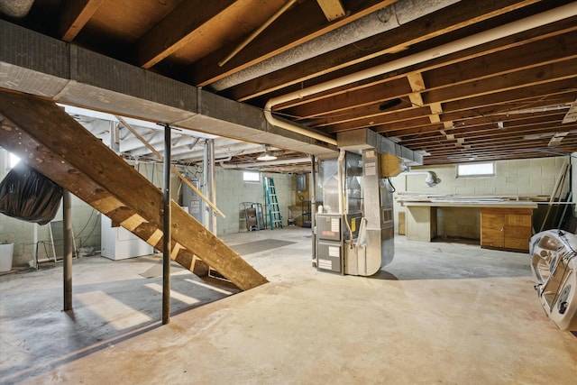 basement with washing machine and clothes dryer, heating unit, and stairs