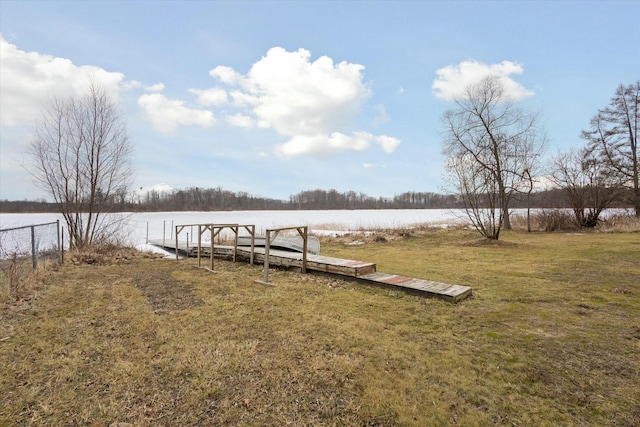 view of dock with a yard, a water view, and fence