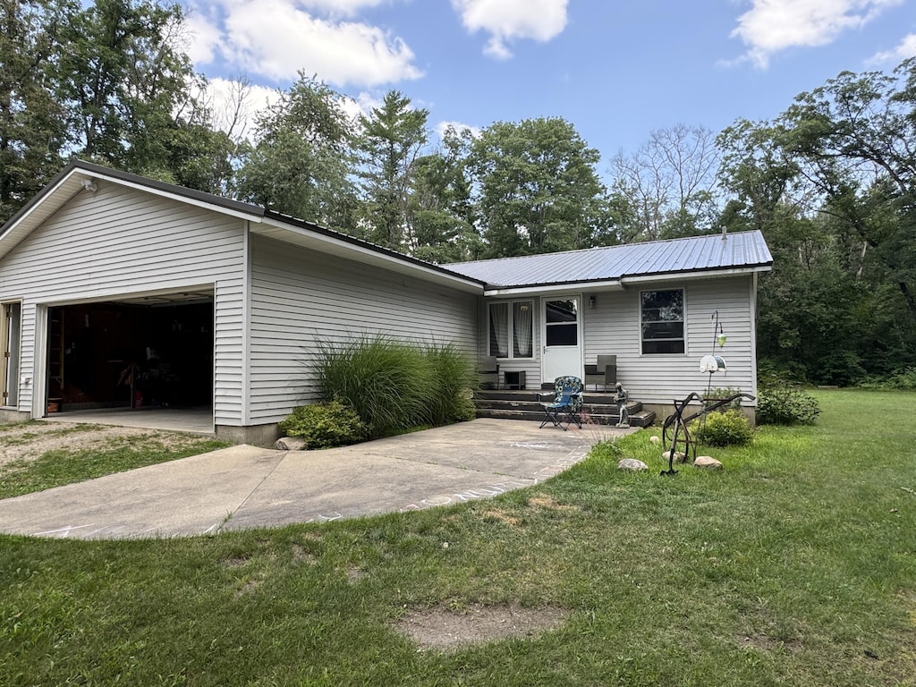 ranch-style house featuring a garage, metal roof, a front lawn, and concrete driveway