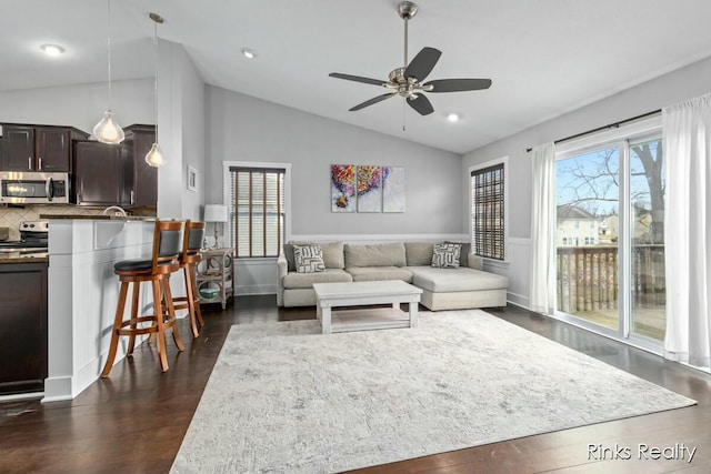 living room featuring ceiling fan, plenty of natural light, vaulted ceiling, and dark wood-type flooring