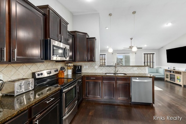 kitchen featuring a peninsula, a sink, open floor plan, appliances with stainless steel finishes, and dark wood-style floors