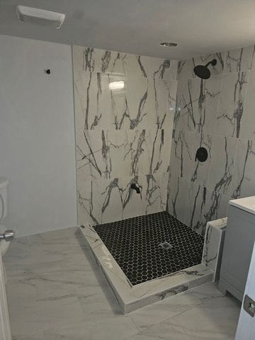 bathroom featuring marble finish floor, a marble finish shower, and vanity