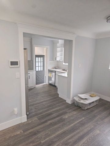 kitchen with dark wood-style floors, baseboards, light countertops, and dishwasher