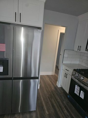 kitchen with dark wood-style floors, stainless steel refrigerator with ice dispenser, black gas stove, and white cabinets