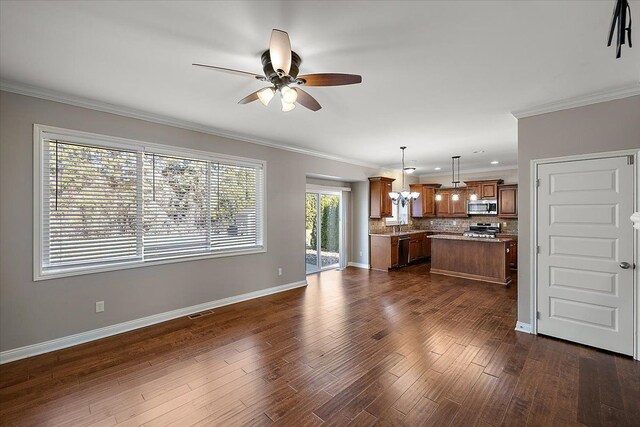 interior space with dark wood-style floors, a kitchen island, crown molding, stainless steel microwave, and tasteful backsplash