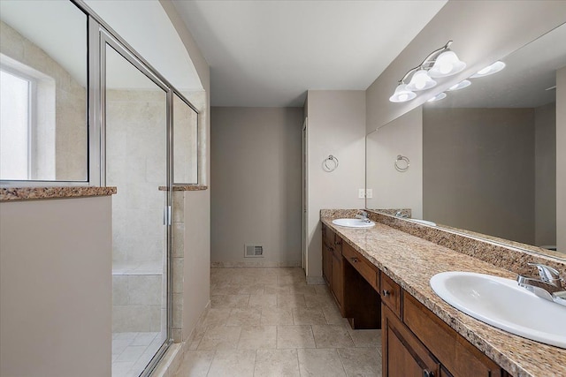 full bath featuring double vanity, visible vents, a shower stall, and a sink