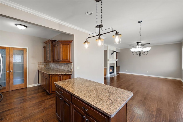 kitchen with tasteful backsplash, baseboards, dark wood finished floors, a fireplace with flush hearth, and ornamental molding