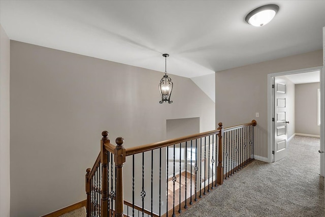 hallway featuring an upstairs landing, carpet flooring, a notable chandelier, and baseboards