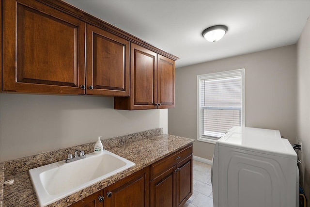 washroom with a sink, cabinet space, light tile patterned floors, baseboards, and washer / dryer