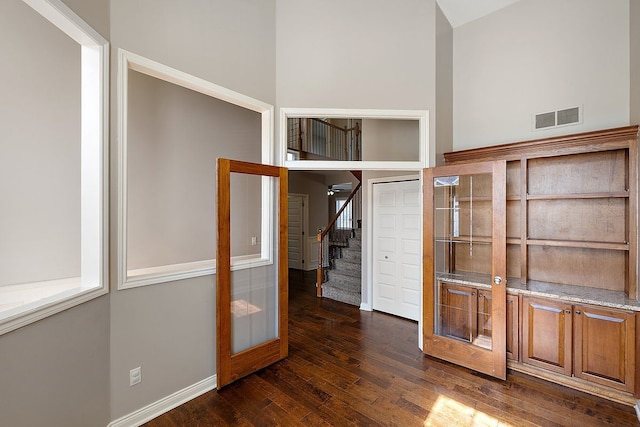 interior space with dark wood finished floors, visible vents, and stairs