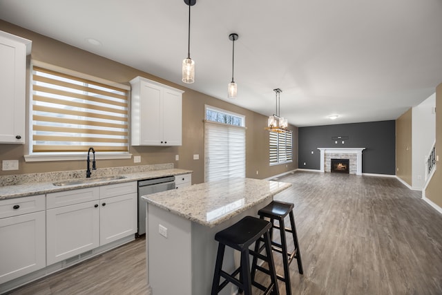 kitchen featuring dishwasher, wood finished floors, a center island, white cabinetry, and a sink