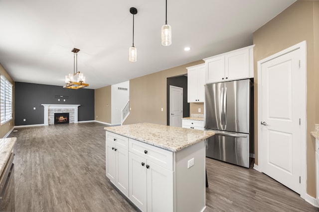 kitchen featuring a kitchen island, appliances with stainless steel finishes, dark wood-type flooring, hanging light fixtures, and a fireplace