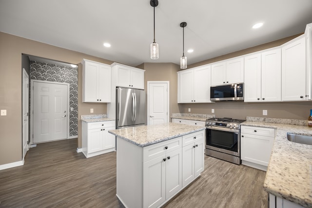 kitchen with a kitchen island, white cabinetry, stainless steel appliances, and wood finished floors