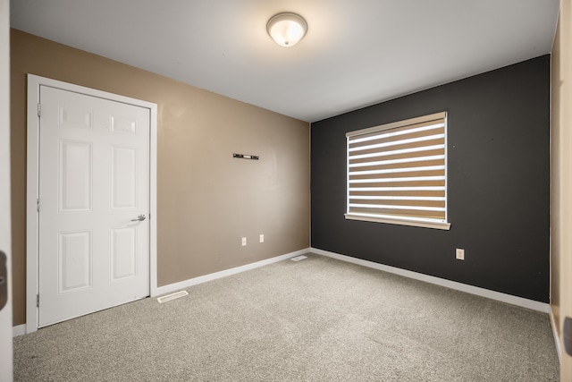 carpeted spare room with visible vents and baseboards