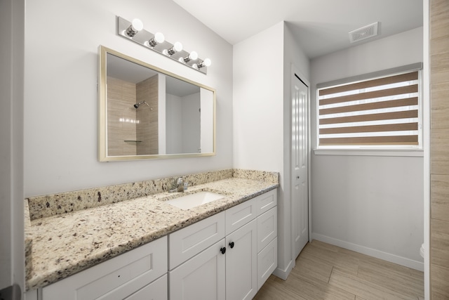 full bath featuring baseboards, visible vents, walk in shower, and vanity