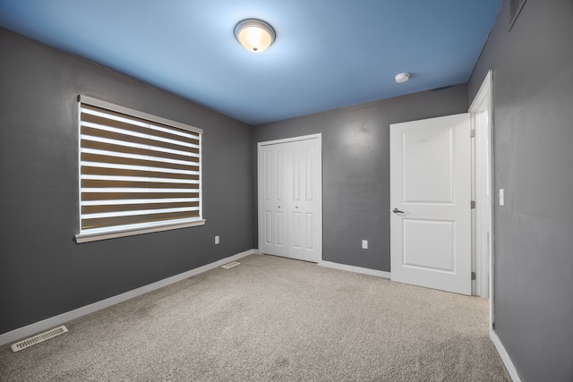 unfurnished bedroom featuring baseboards, a closet, visible vents, and carpet flooring