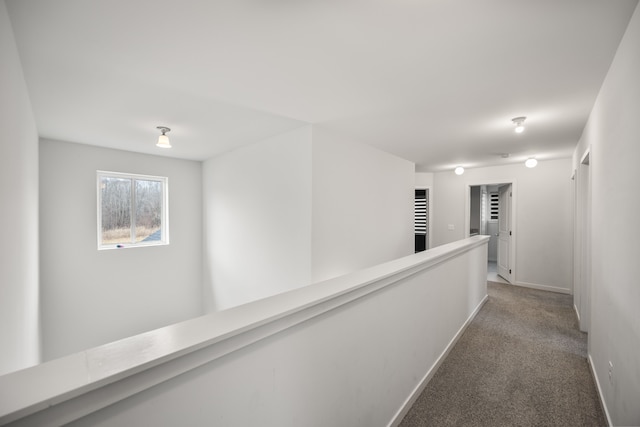 hallway with carpet, an upstairs landing, and baseboards