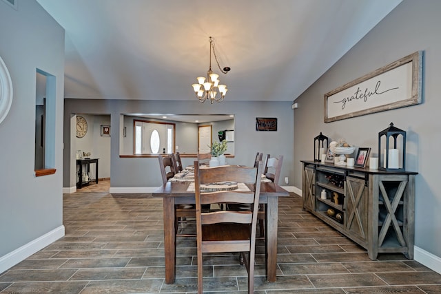 dining space featuring lofted ceiling, wood tiled floor, a chandelier, and baseboards