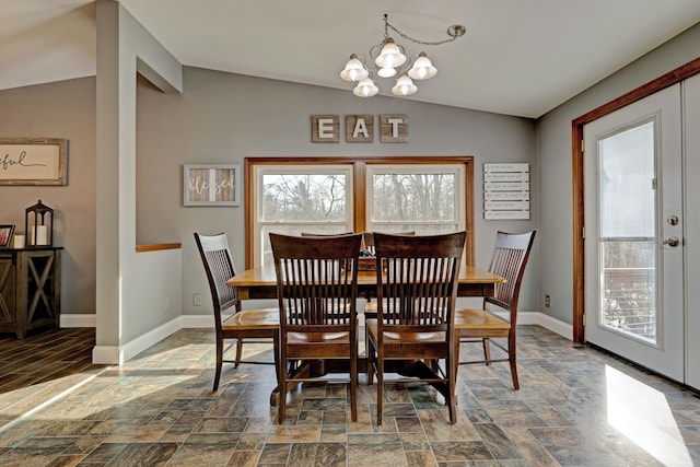 dining space featuring vaulted ceiling, stone finish floor, a notable chandelier, and baseboards