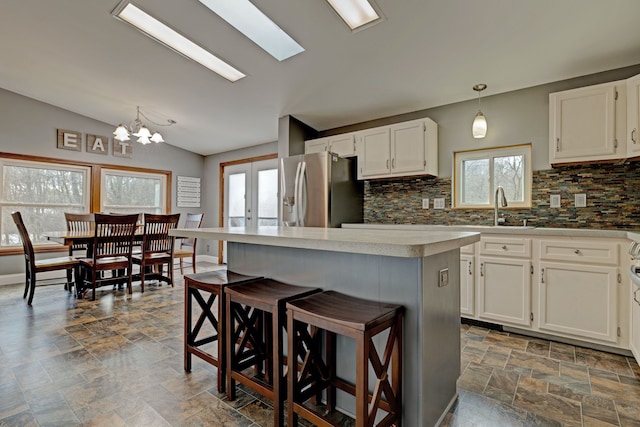 kitchen with stainless steel fridge, a breakfast bar area, white cabinets, and french doors